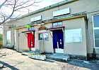 男湯と女湯の入り口が分けられた間に木製看板が設置された、ベージュ色の外壁の大門の湯の建物外観の写真