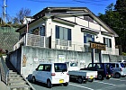 駐車場が完備され、階段を上がった先に建つ白壁の天王寺穴原湯の建物外観の写真