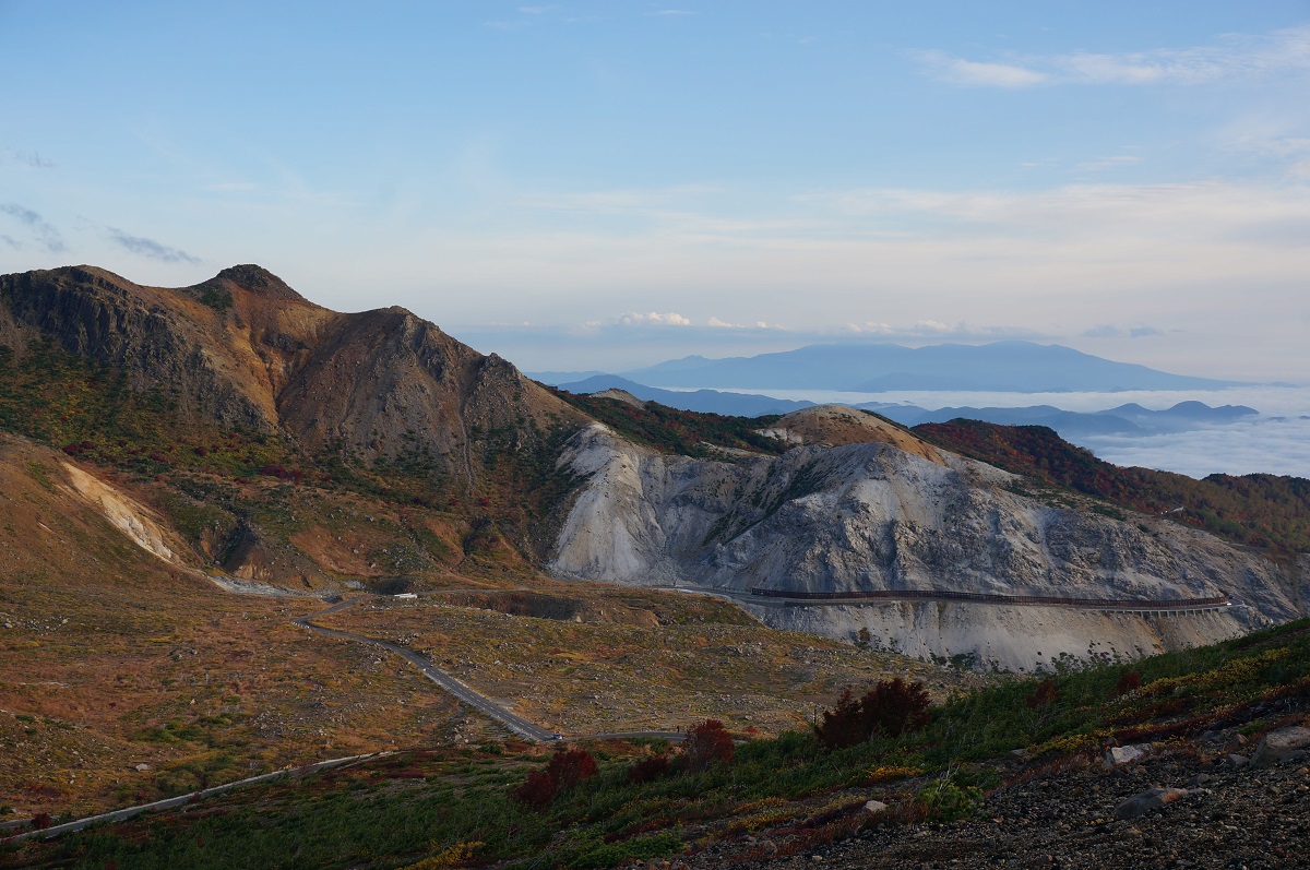 遠くに見える山が靄に隠れている、冬の磐梯吾妻スカイラインの写真