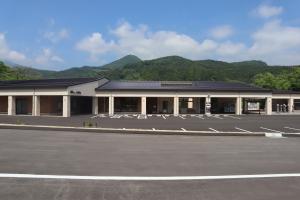 山の麓に建つ黒い屋根で白い外壁の湯愛舞台の建物外観の写真