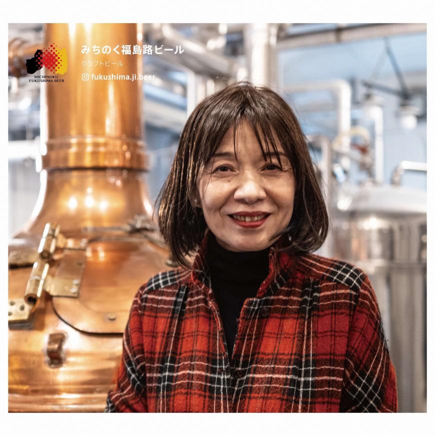 路ビールの醸造所の中に立つ、赤のチェック柄のシャツを着た常務取締役の吉田さんの写真