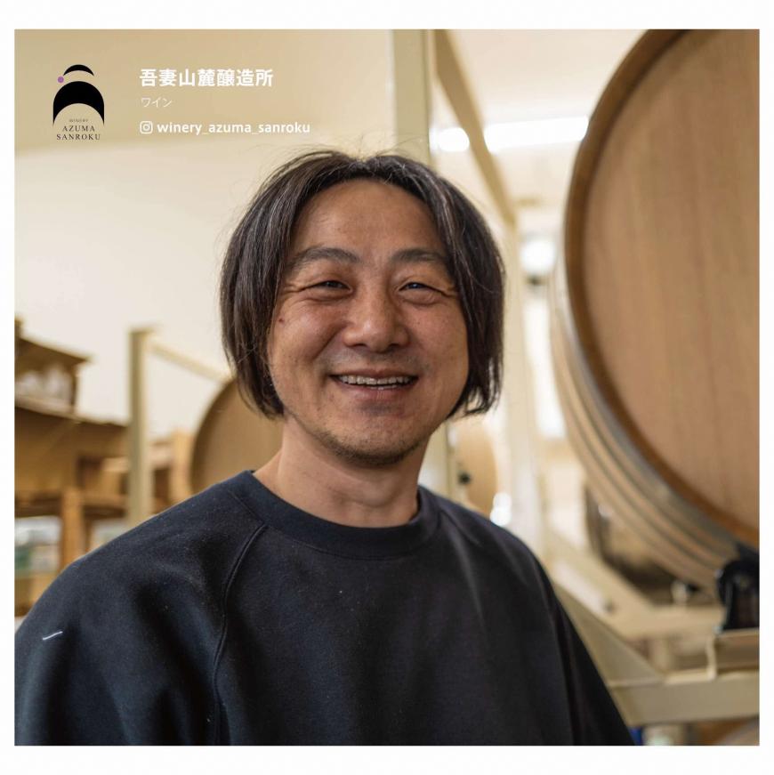 醸造所内の大きな樽の前に立つ牧野社長の写真