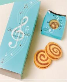 水色地で音記号や音符が描かれたパッケージの個包装された袋と箱、渦巻き模様の2枚のクッキーが置かれた写真