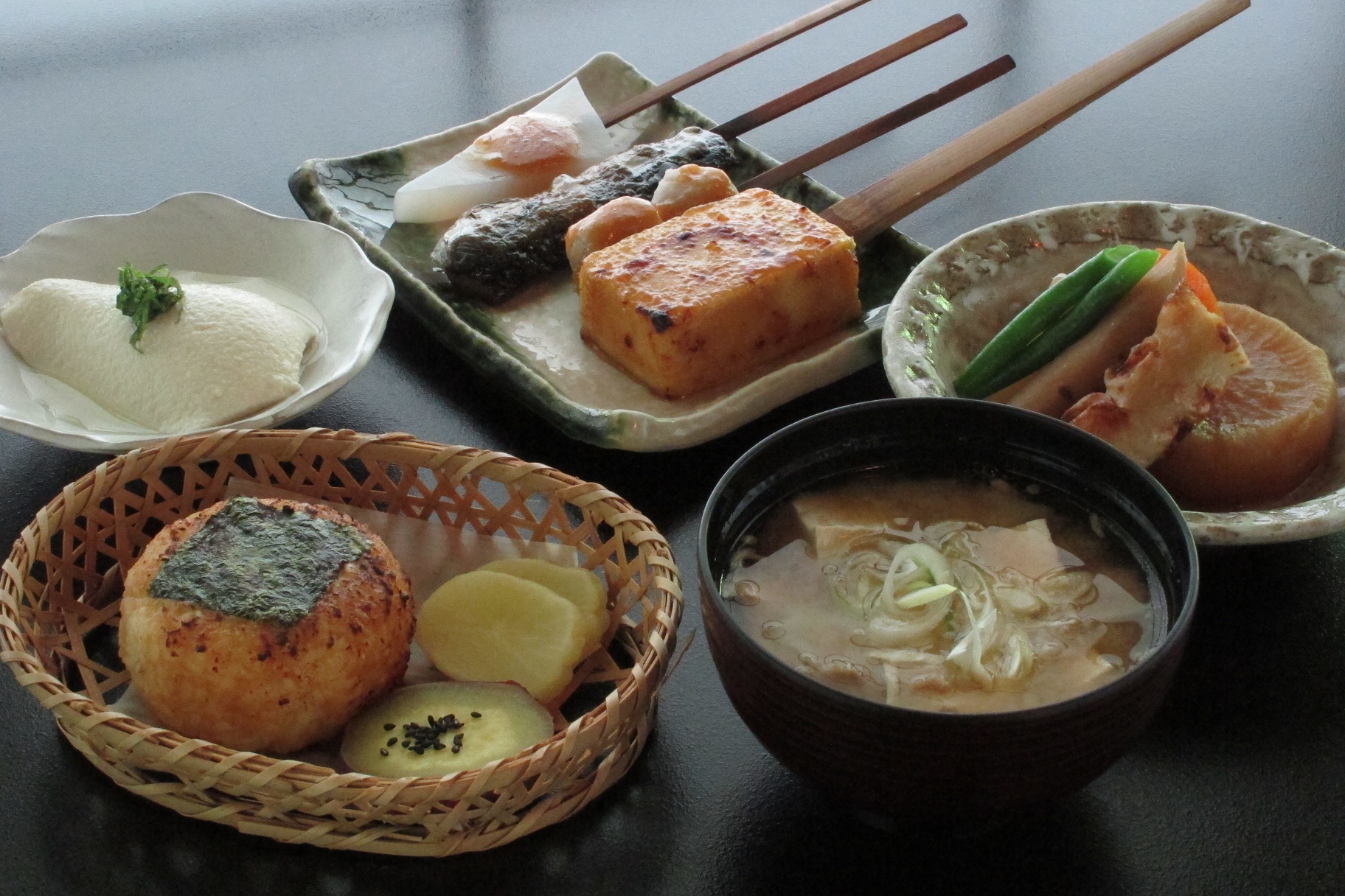 5つの容器に豆腐で作られたゆずみそ焼きおにぎり、田楽、煮物などの料理が盛り付けられた写真