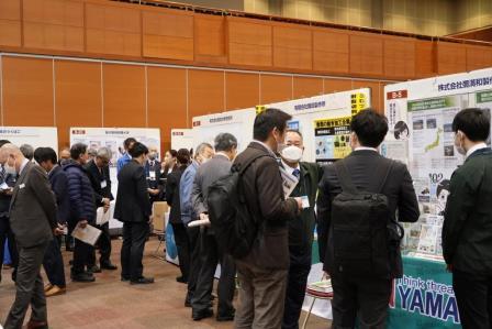 パネル展示されたブースの担当者に話を聞いている参加者の写真