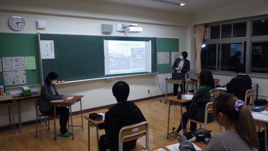 資料が映し出された黒板の右側に立つ女性担当者の話を、自席に座った生徒たちが熱心に聞いている写真