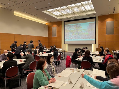 各机に別れグループごとに話し合いがされている会議の様子の写真