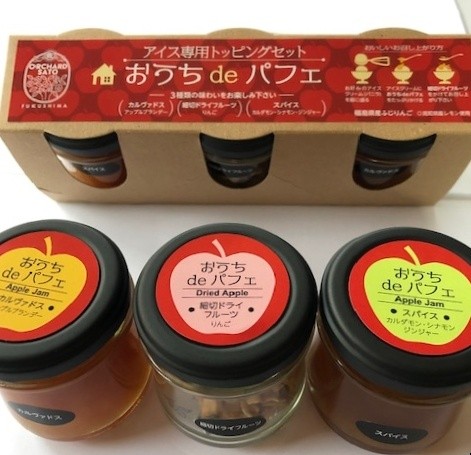 3種類の商品が入った、「おうちdeパフェ」と書かれた赤いラベルが貼られたパックの前に、蓋に、黄色、ピンク、黄緑色のシールが貼られた種類の違う3種類の商品の瓶が並んでいる写真