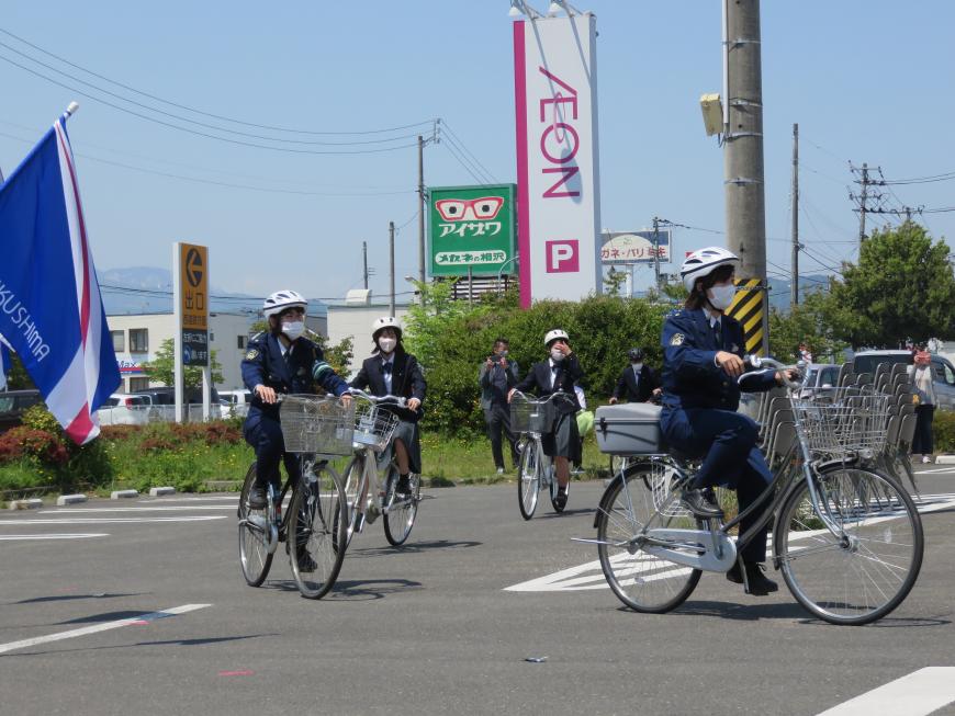 ヘルメットをかぶった女性警察官2名の自転車に続き、ヘルメットをかぶった女子高校生2名が自転車に乗って走っている写真