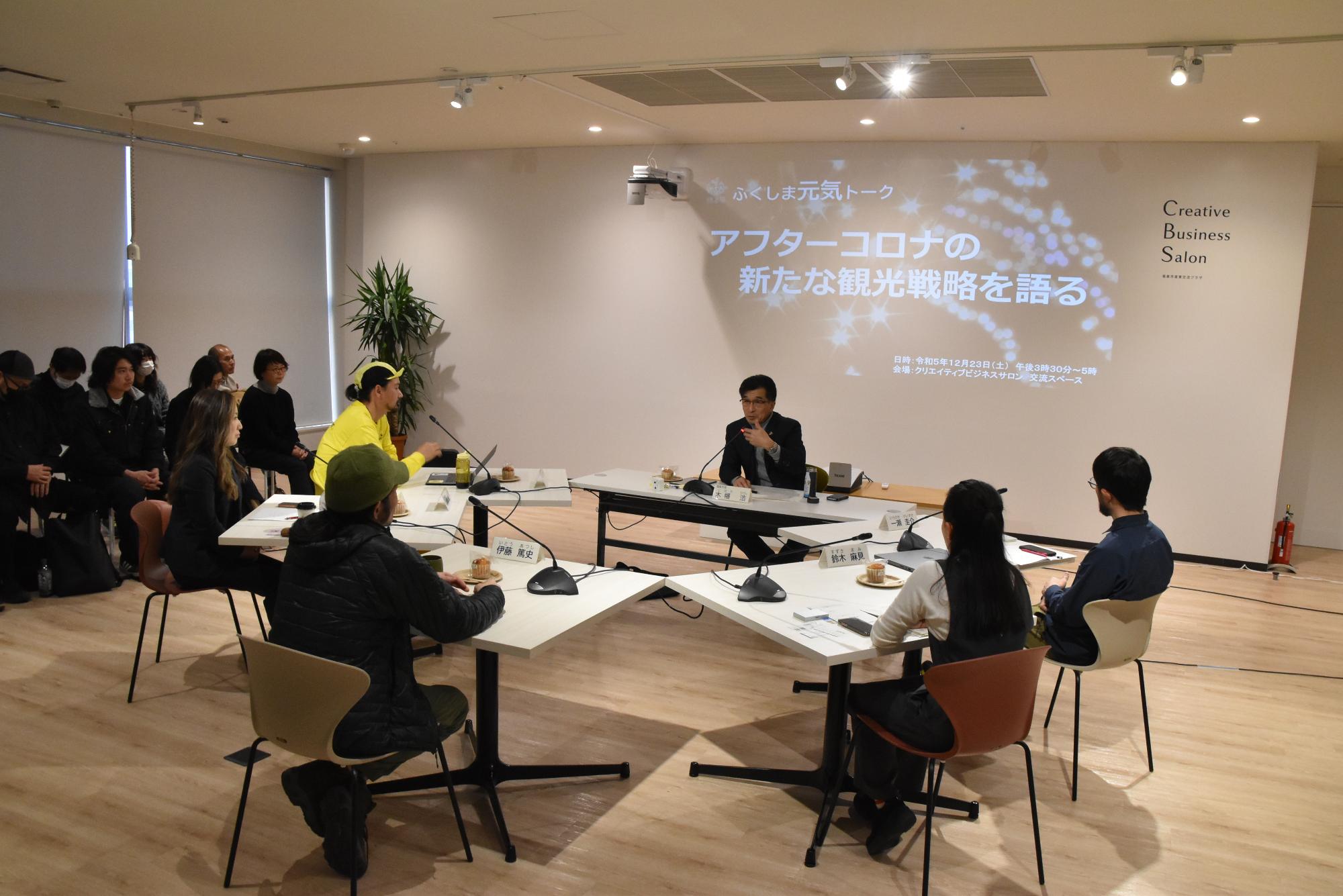 スクリーンに「ふくしま元気トーク アフターコロナの新たな観光戦略を語る」資料が映し出される前の席で講師の方が話をしている様子を参加者が真剣に聞いている写真