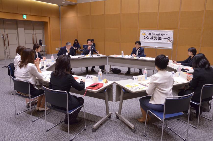 机の上に資料が置かれネームプレートの席に参加者が座り、意見交換会が行われている様子の写真