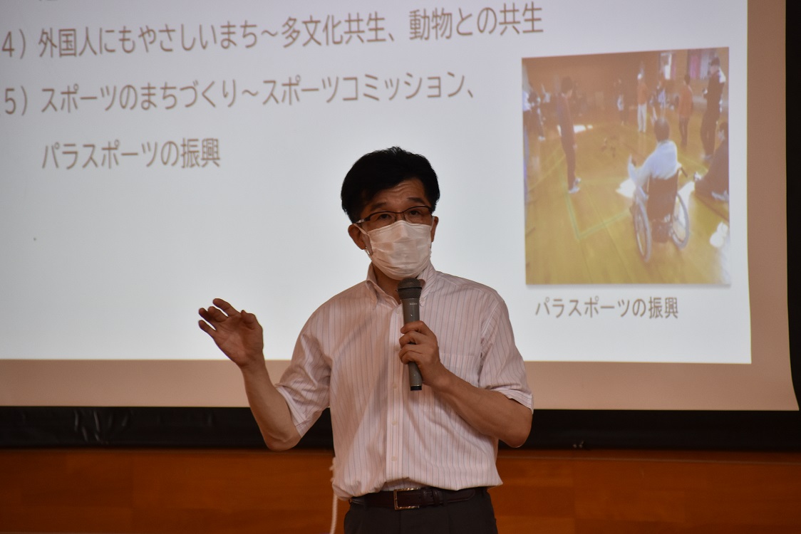 資料が映し出されたスクリーンの前でマイクを持ち話をしている市長をアップで撮影した写真