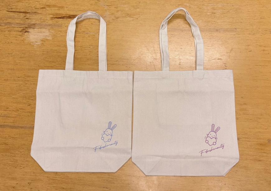 薄いベージュのトートバッグが2つ並び、それぞれ右下に「ももりん」のイラストとロゴが入っており、ひとつは青、もうひとつは赤のデザインのトートバッグの写真