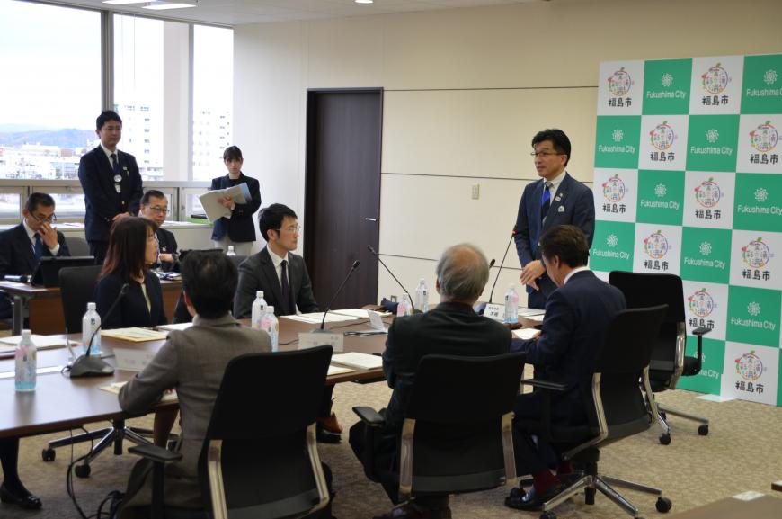 福島市のバックボードの前に立って挨拶をする市長、その方向を向き聞いている関係者達の写真
