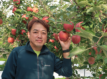 片平 聡さんが真っ赤な林檎を持っている写真（片平 聡さんのページへリンク）