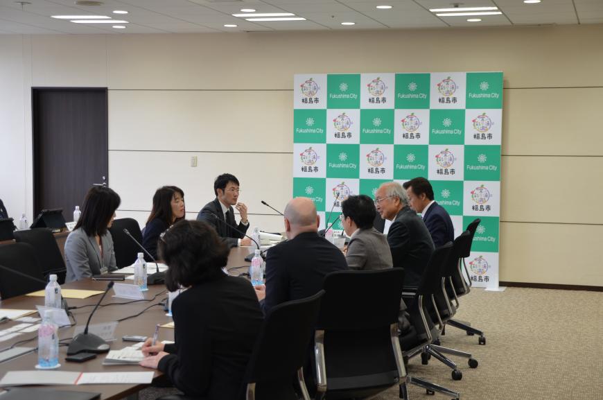 中央に置かれたテーブルの両側に関係者達が座り、検討委員会が行われている様子の写真