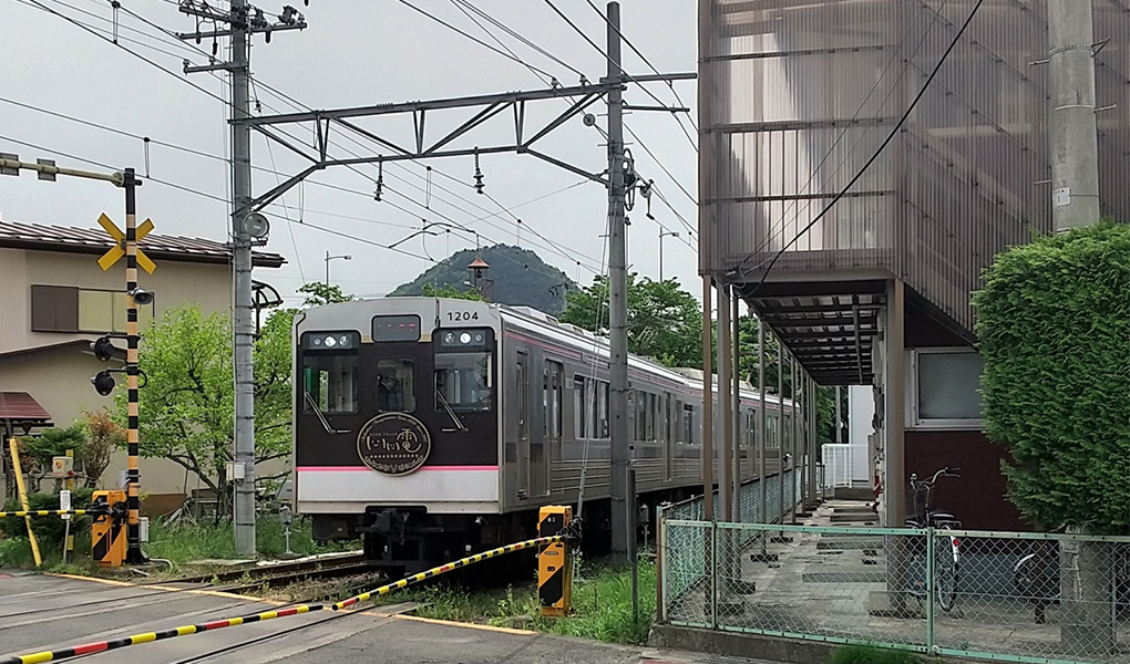 遮断機の前を電車が通過する様子の写真