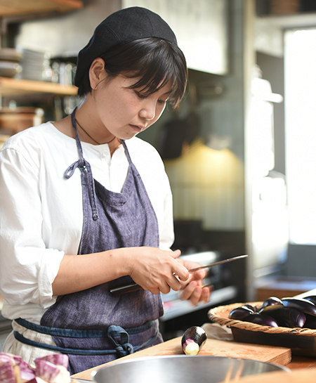 真剣な表情でナスに包丁を入れる近藤 仁美さんの写真