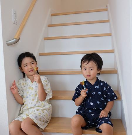 甚平を着た女の子と男の子が階段に座って飴を食べている写真
