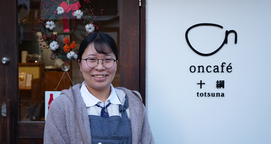 「oncafé totsuna」のロゴがある入口前にいる宮司 君香さんの写真