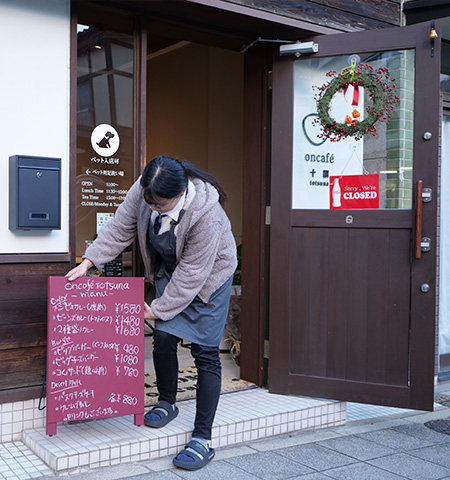 メニュー表の看板を外に設置しようとする宮司 君香さんの写真