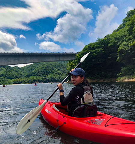 赤いカヌーに乗ってパドリングする宮司 君香さんの写真