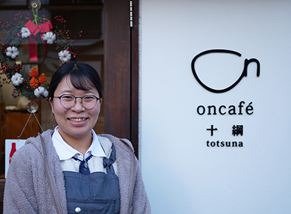 「oncafé totsuna」のロゴがある入口前にいる宮司 君香さんの写真（宮司 君香さんのページへリンク）