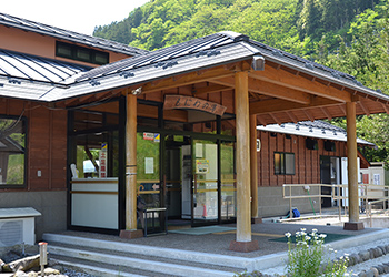 木を基調とした外壁で入り口上に「もにわの湯」と書かれた木製看板が設置された建物外観の写真