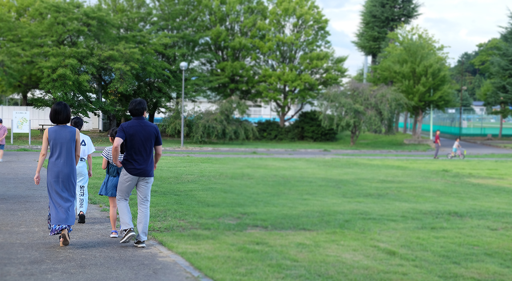 公園を散歩する中島 明日香さん家族の後ろ姿の写真
