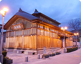 木造のレトロな飯坂温泉が街灯に照らされている建物の外観写真
