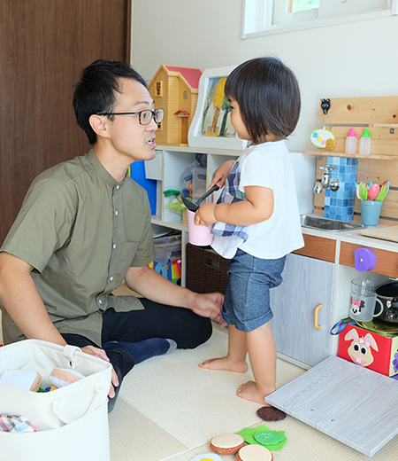篠田 大輔さんと娘さんが向かい合い遊んでいる写真