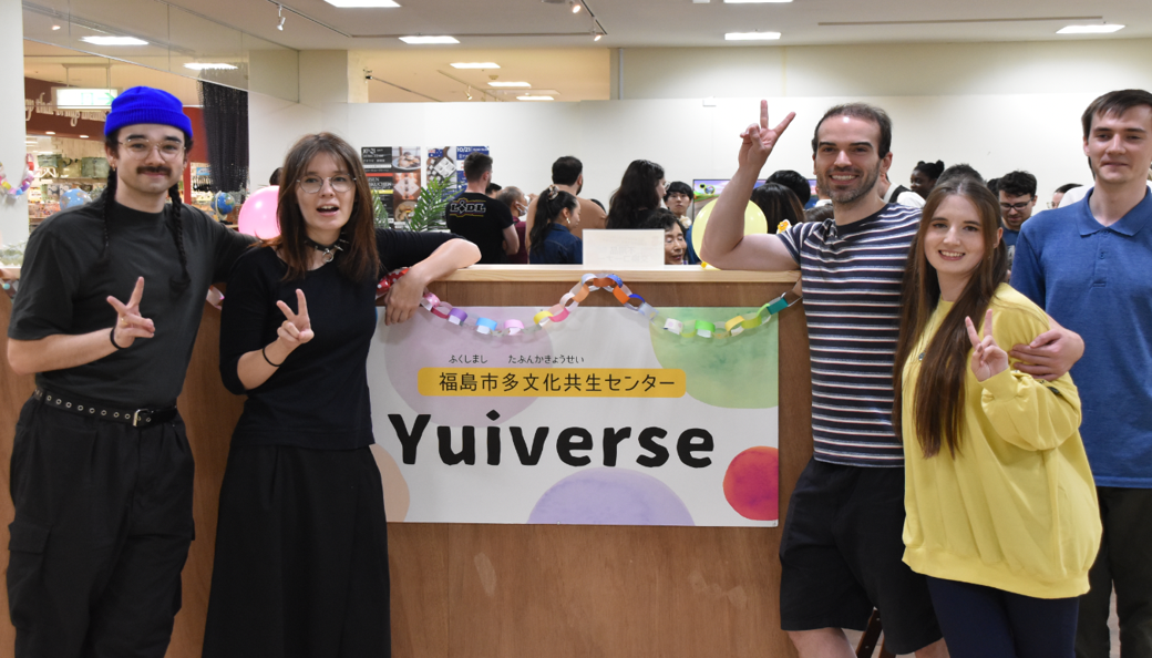 「福島市多文化共生センターYuiverse」と書かれたボードの周りで5人の外国人の方がピースサインをして立っている写真