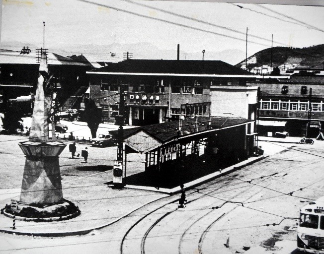 奥に大きな建物、中央付近に駅ホーム、道路には路面電車の線路がある福島駅前発着所を写した白黒写真