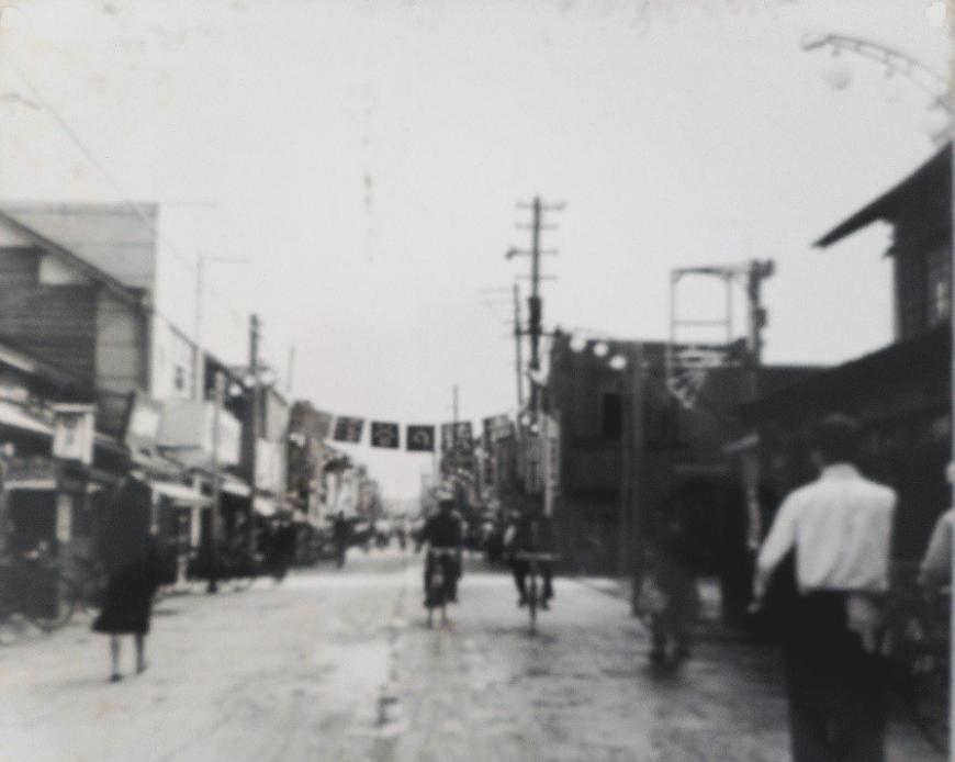 両側に建物が立ち並び、中央の通りを歩いている人、自転車に乗っている人などが行きかっている福島日活館近辺を写した白黒写真