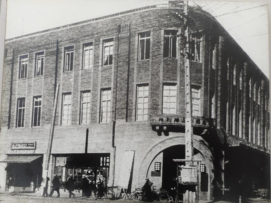 四つ角に面した建物の角が丸みがかり、長方形の窓がたくさん並ぶ福ビルを写した白黒写真