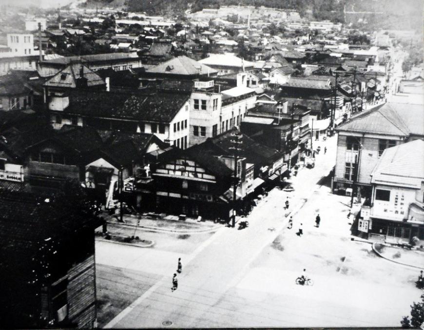 中央に大きな道が1本まっすぐ伸び、道の両側には建物が沢山建っている様子を写した白黒写真
