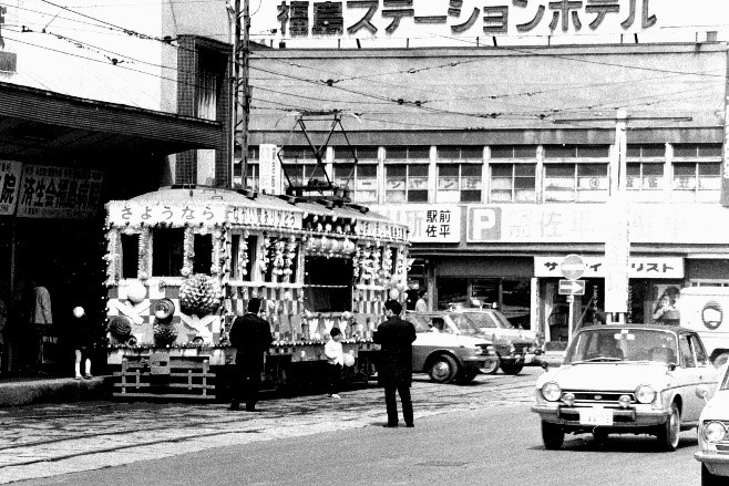 福島ステーションホテルの前に「さようなら」の横断幕を掲げ車両全体が装飾された路面電車が停車している白黒写真