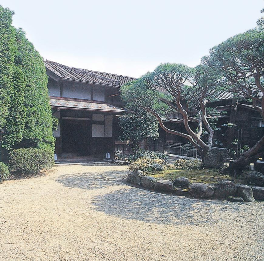 砂利の庭園の奥に建つ御倉邸の写真
