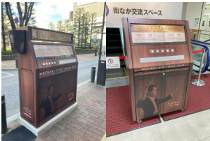 左：木目調のデザインで、ボックスの下部に指揮をしている古関裕而氏のラッピングが貼られ街頭に設置されている応援歌ボックスの写真。右：木目調のデザインで、ボックスの下部に指揮をしている古関裕而氏のラッピングが貼られ街なか交流スペースの赤いマットの上に設置されている応援歌ボックスの写真。