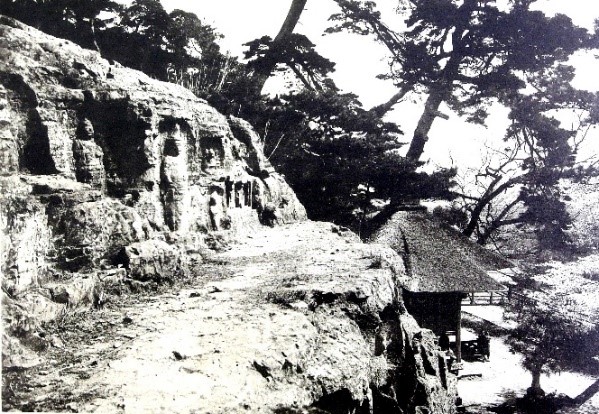細い道の横にある斜面の岩に彫られた岩谷観音の白黒写真
