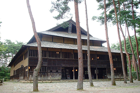 細い幹の木々が生えている奥に建っている旧広瀬座の外観写真