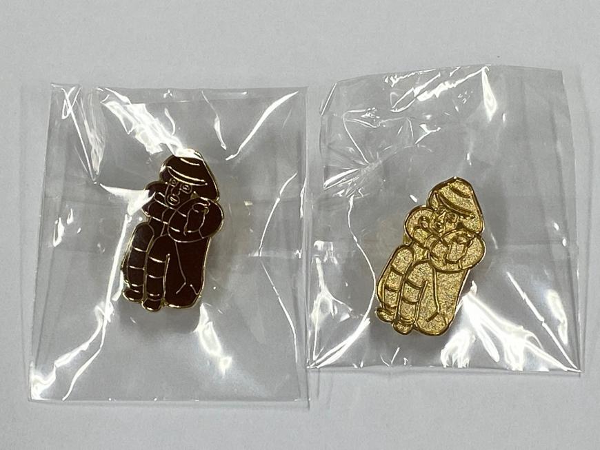 しゃがむ土偶を模った茶色と金色の土偶ピンバッジの写真
