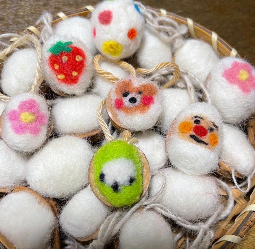 果物や花、動物などが描かれた羊毛のくるみチャームがカゴに入っている写真