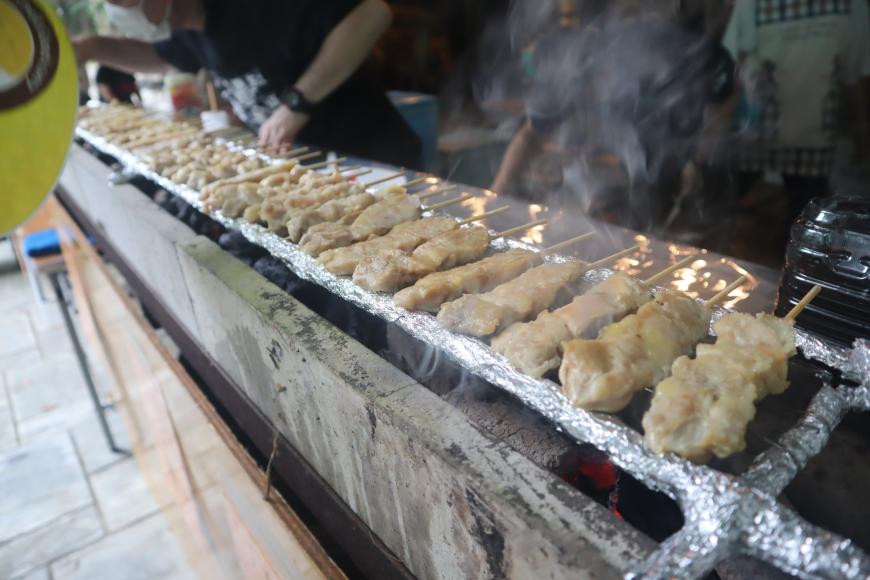 横に長い焼き鳥コンロの上に沢山の焼き鳥が並べられて焼かれている写真