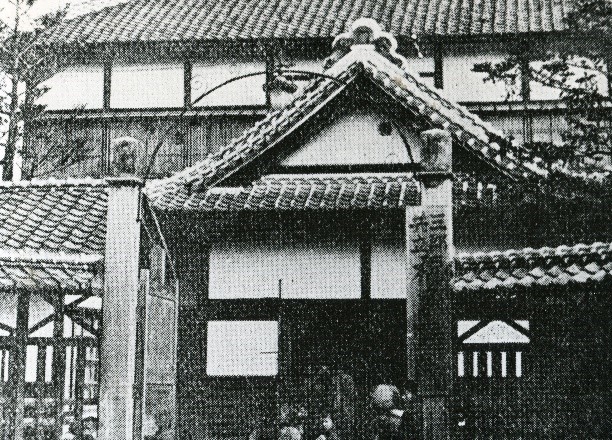 瓦屋根の木造で門柱に看板がたてられている明治時代の三郡共立福島病院の白黒写真