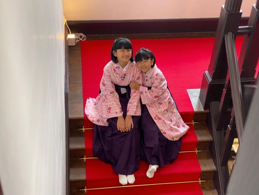 花の写真館の階段の踊り場に座っている袴姿のまーちゃんおーちゃんの写真