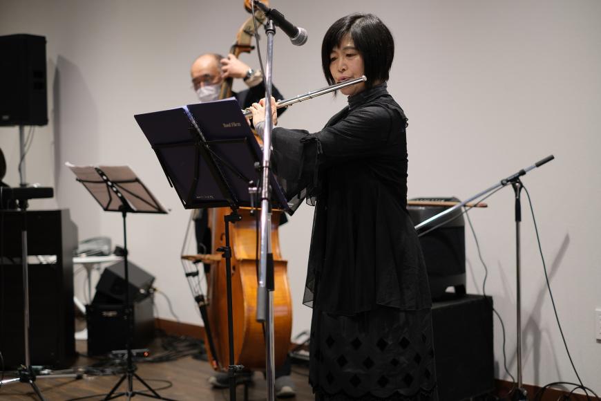 黒の衣装を着た若月美香さんがフルートを演奏している写真