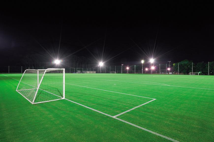 整備された緑色の芝生の上にサッカーゴールと白いラインが引かれ、ライトアップされている十六沼公園サッカー場の写真