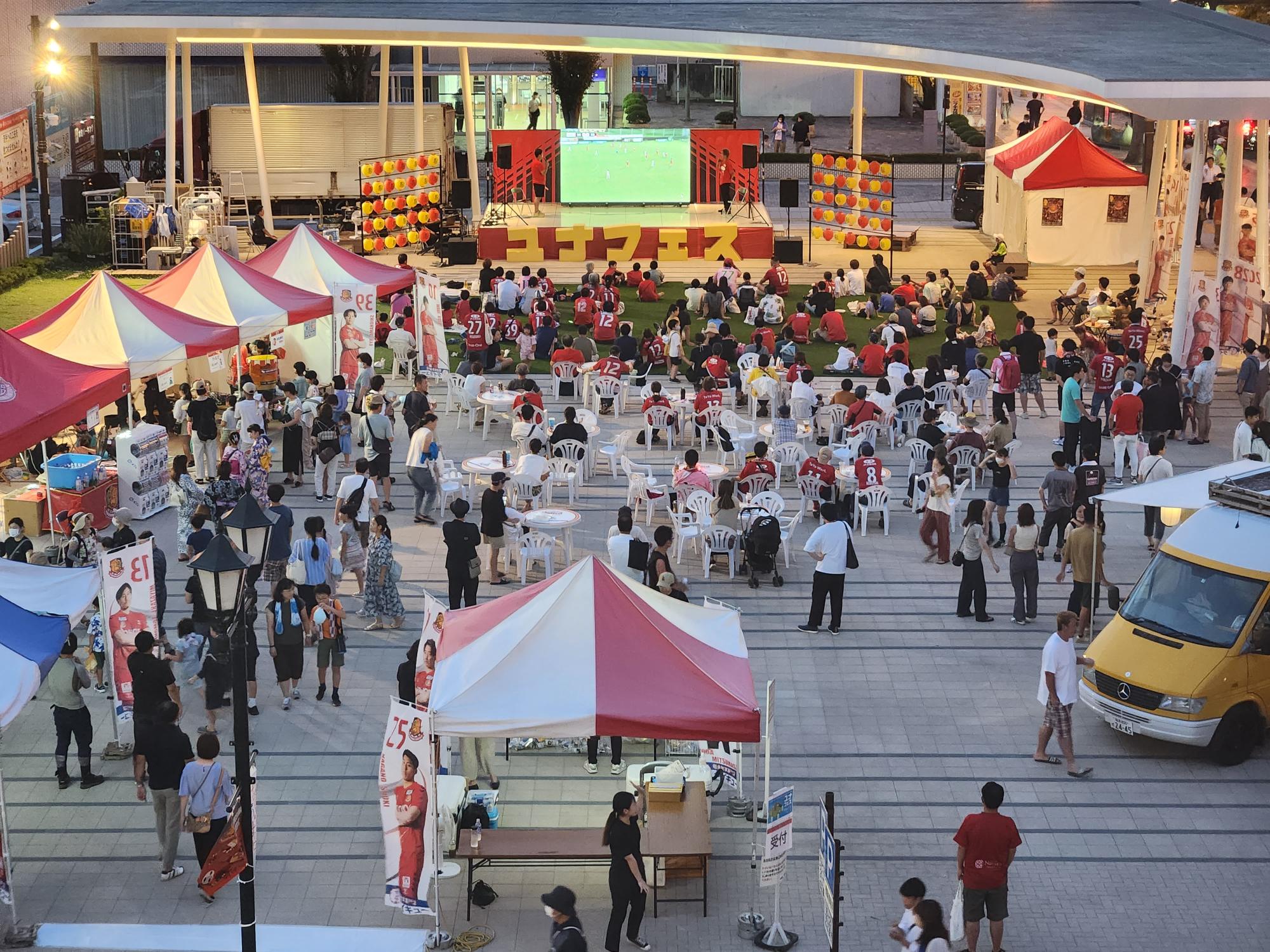 左側に白と赤色のテントが複数並び、奥にはステージなどが設置されているユナフェスイベント会場全体を写した写真