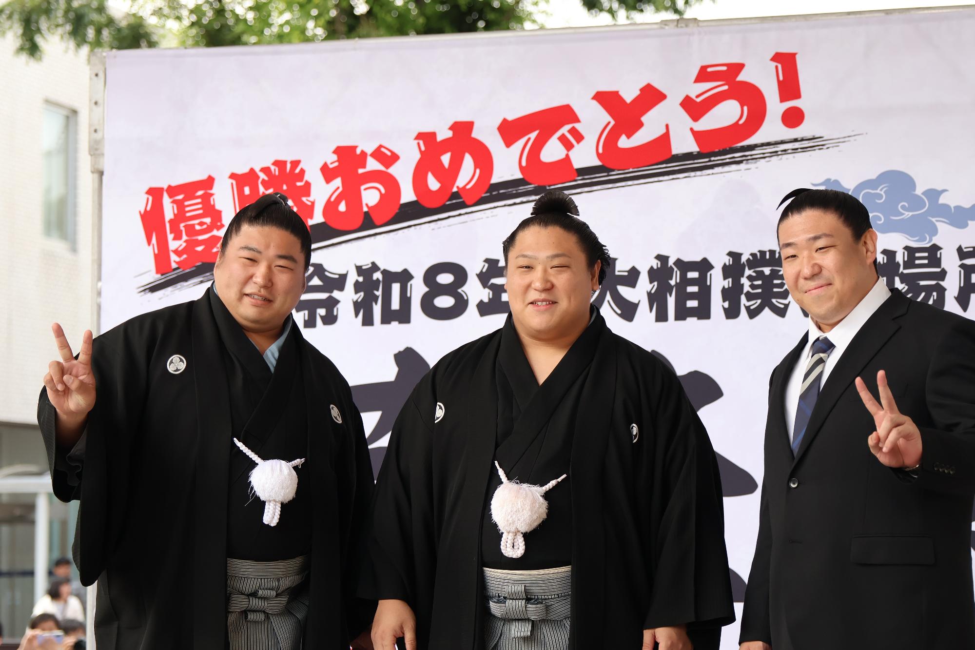 横断幕をバックに写る大波三兄弟（左から若元春、若隆景、若隆元）